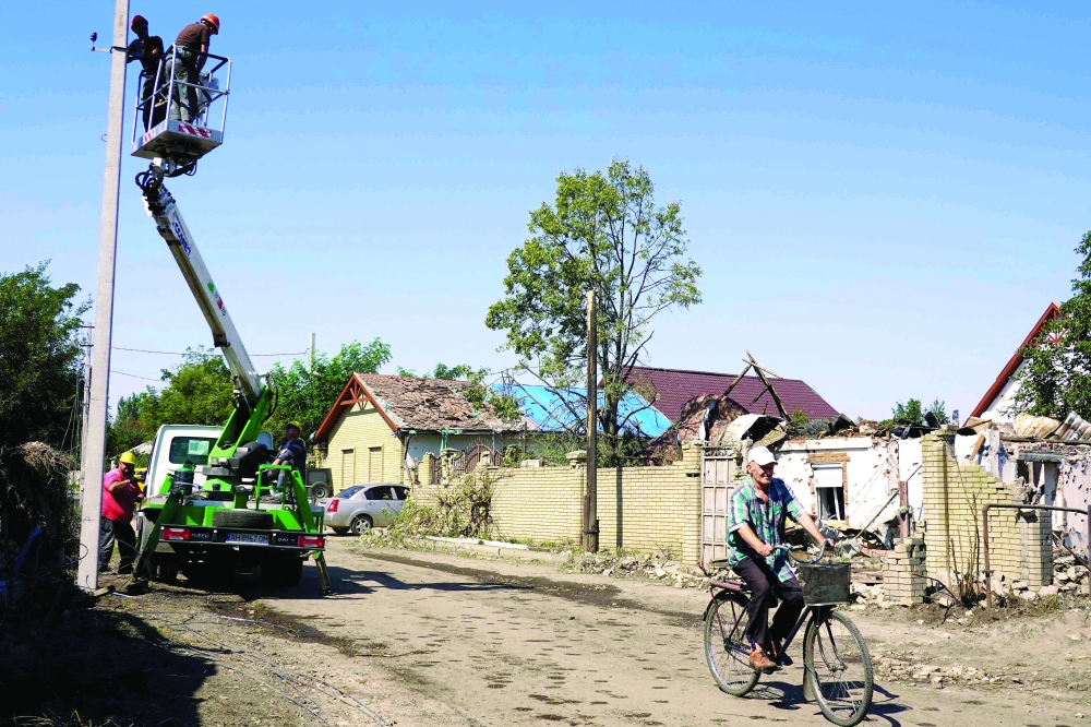 Workers repair power line next to damaged houses, in Sloviansk. — AFP