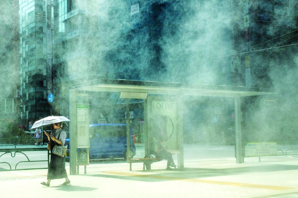 A woman with an umbrella walks in the scorching sun in Tokyo. — AFP