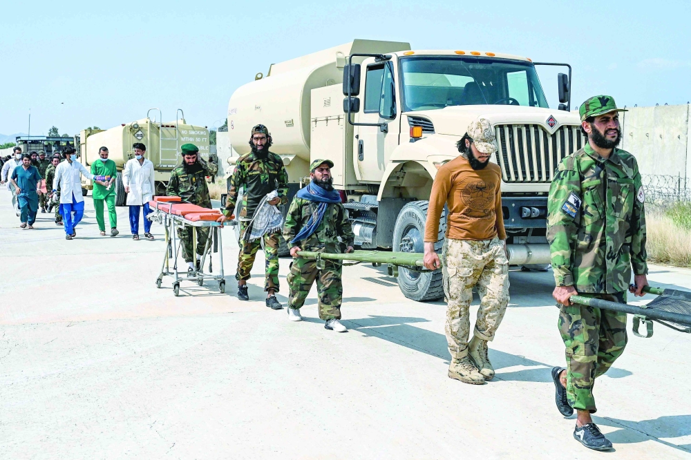 Afghan medical and security personnel carry stretchers for evacuated earthquake victims, in Jalalabad. — AFP