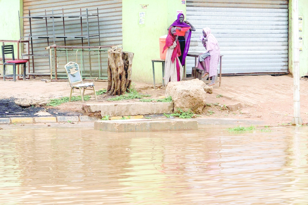 Women gather along the side of a flooded street in Sudan's capital Khartoum. — AFP