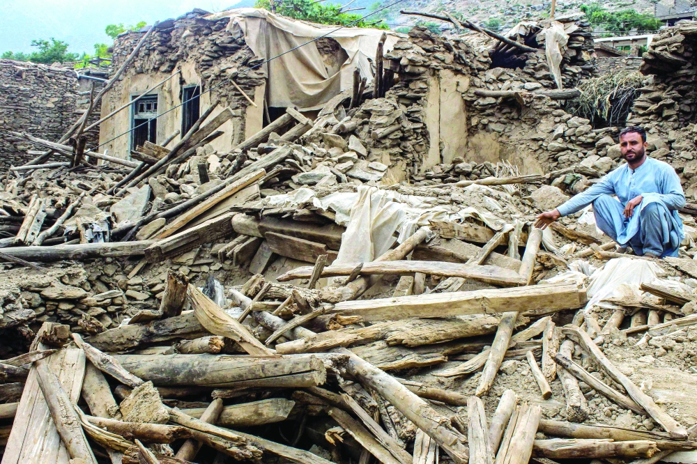 A man sits amid the remains of a damaged house in the aftermath of an earthquake at the Darai Nur district of Nangarhar province on Wednesday. — AFP