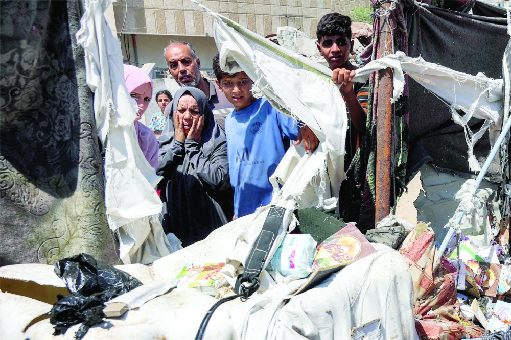 People inspect damages at a tent encampment that was sheltering displaced people, after it was hit by Israeli bombardment, near Al Shifa Hospital in Gaza City. - AFP