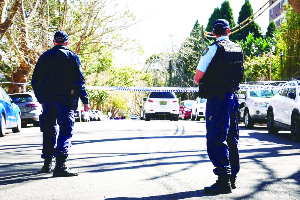 Police officers stand in front of police tape across a road in Sydney. — AFP