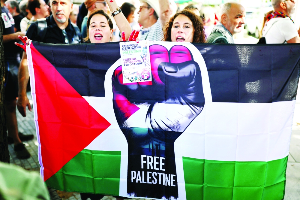Protesters hold a Palestinian flag during a pro-Palestinian demonstration in front of the Israeli Embassy in Madrid, on September 6, 2025. Israel's retaliatory offensive to the 2023 Hamas attacks has killed at least 64,300 Palestinians, most of them civilians, according to figures from the health ministry in Hamas-run Gaza that the United Nations considers reliable. Hamas's 2023 attack resulted in the deaths of 1,219 people, mostly civilians, according to a tally based on official figures. Hamas also took 251 hostages.