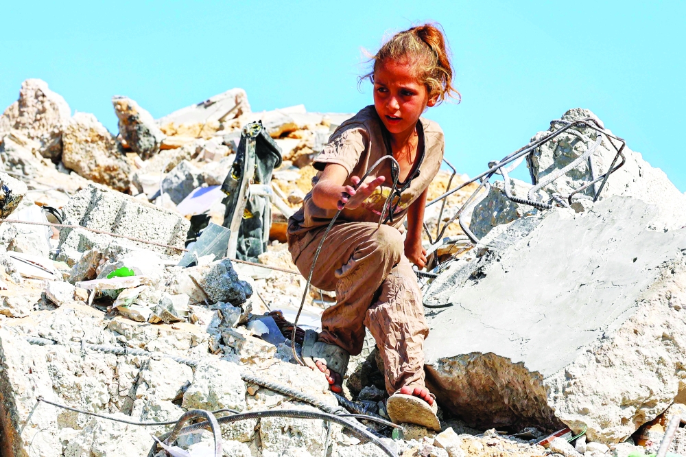 A girl searches for salvage at the mound of rubble at the site of the collapsed Sussi Tower, which was destroyed earlier by Israeli bombardment, in Gaza City on Saturday. — AFP