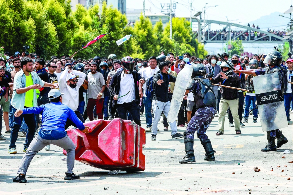 Demonstrators weild stones and sticks as they clash with riot police personnel, in Kathmandu. — AFP 
