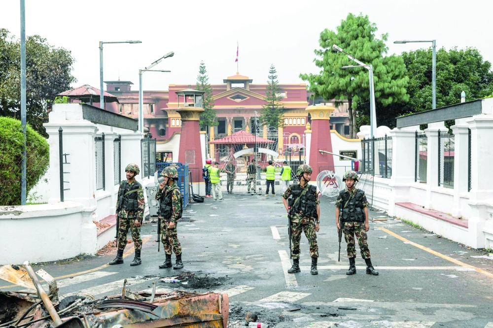 Army personnel stand near charred remains outside the torched President House in Kathmandu. — AFP
