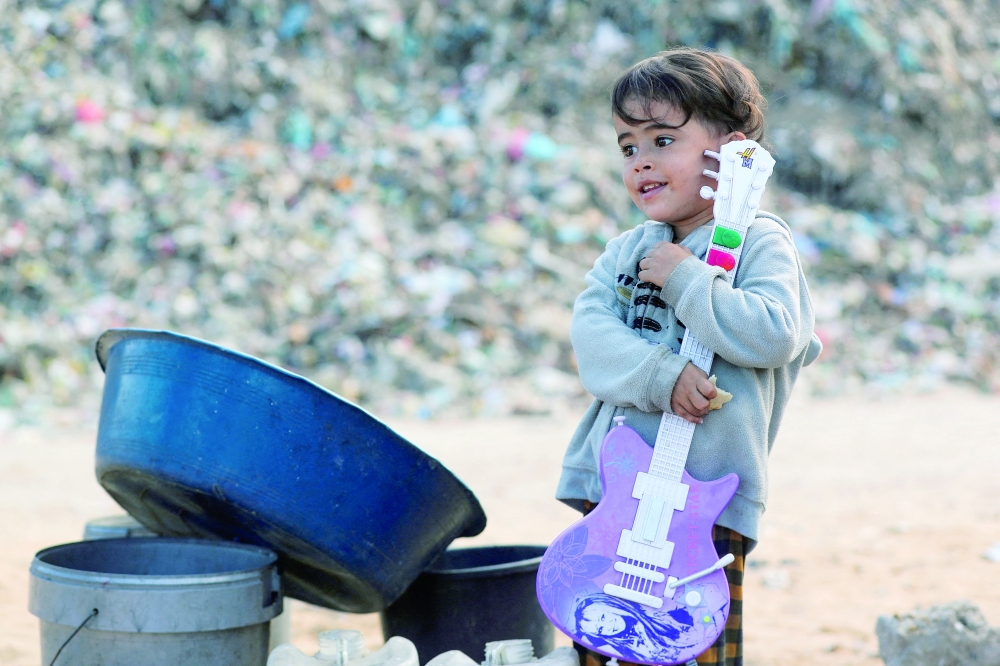 A displaced Palestinian boy holds a toy guitar near a dump site where he shelters with his family in the central Gaza Strip on Wednesday. - Reuters