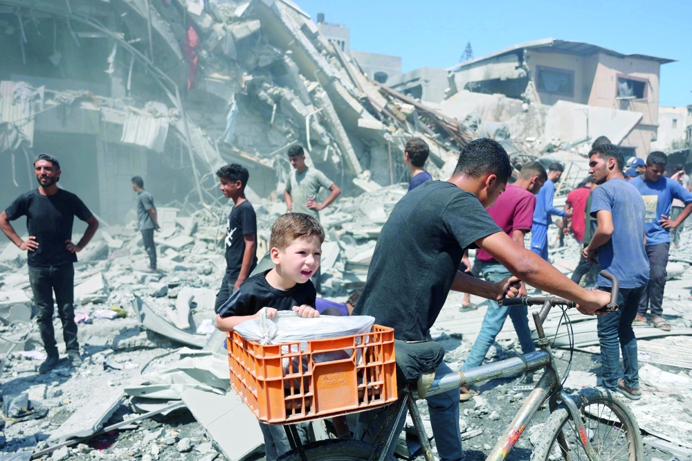 Palestinians walk past a destroyed building after an Israeli strike on Al Nassr Street in Gaza City on Friday. — AFP