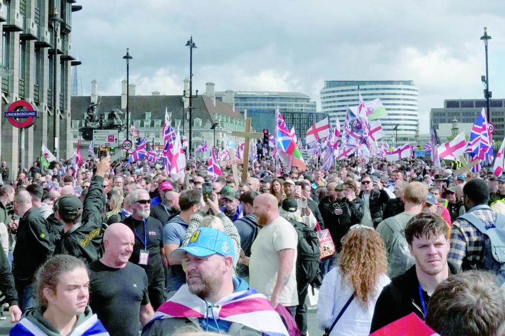 Supporters of British far-right activist Tommy Robinson, whose real name is Stephen Yaxley-Lennon, wave Union flags and St George's cross and Welsh flags as they walk through central London during a 'Free speech' march, on September 13, 2025.  (Photo by CARLOS JASSO / AFP)
