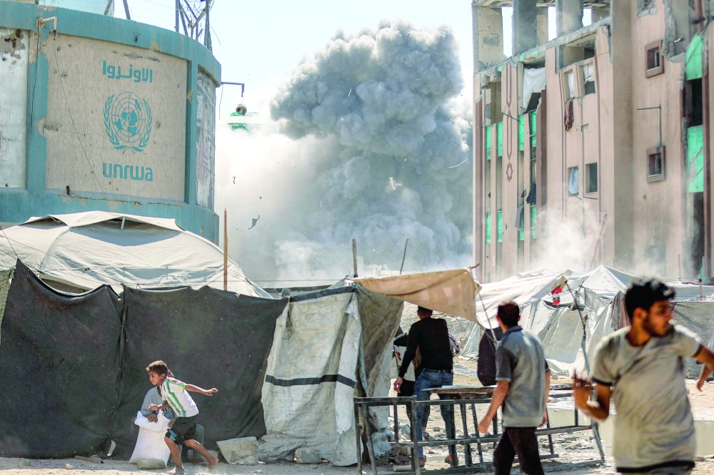 People run from an Israeli strike on a building, in Gaza City. — AFP