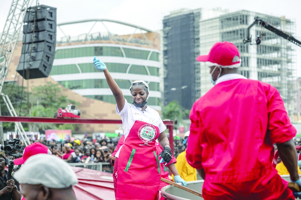 Nigerian chef Hilda Baci (L) dances as she stands next to a giant pot during an attempt to break the world record for the largest pot of Jollof rice, led by Nigerian chef Hilda Baci in Lagos, on September 12, 2025. 