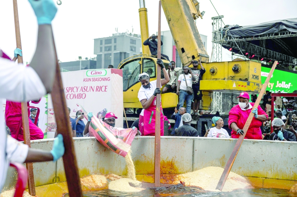Nigerian chef Hilda Baci (C) stirs rice as staff members pour rice in a giant pot during an attempt to break the world record for the largest pot of Jollof rice, led by Nigerian chef Hilda Baci in Lagos, on September 12, 2025. 