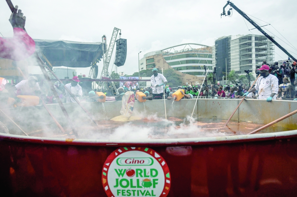 Staff members stir rice as other pour water in a giant pot during an attempt to break the world record for the largest pot of Jollof rice, led by Nigerian chef Hilda Baci in Lagos, on September 12, 2025. 