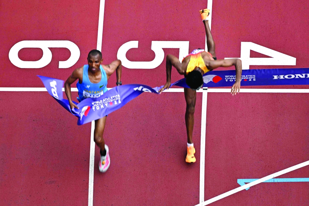 TOPSHOT - Germany's athlete Amanal Petros (R) falls as he crosses the finish line behind Tanzania's athlete Alphonce Felix Simbu (L) in the men's marathon final during the World Athletics Championships in Tokyo on September 15, 2025. (Photo by Antonin THUILLIER / AFP)
