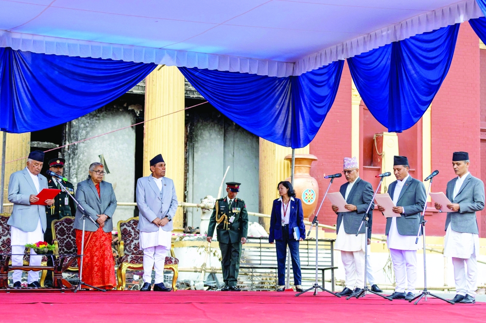 Nepal's newly-elected PM of interim government, Sushila Karki (3L), looks on as President Ram Chandra Paudel (L) administers the oath of office to the country's newly appointed ministers, at the President House in Kathmandu. — AFP