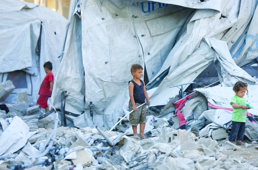 
Palestinian children stand at a tent camp sheltering displaced people, in Gaza. — Reuters 
