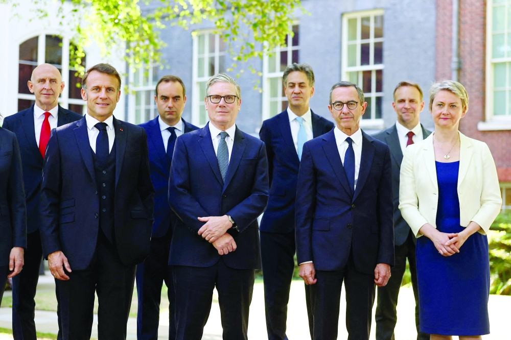 Britain's PM Keir Starmer (C) and France's President Emmanuel Macron (L) pose for a family photo with delegates during the UK-France Summit at 10 Downing Street in London. — AFP file photo