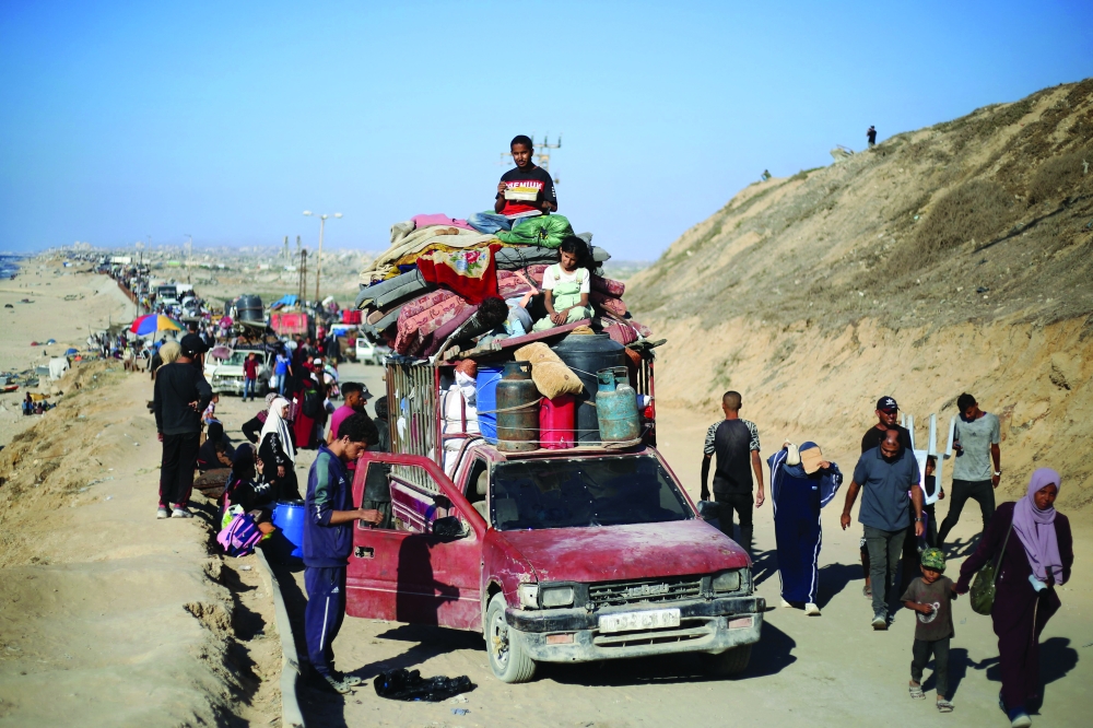 Displaced Palestinians move with their belongings southwards on a road in the Nuseirat camp. — AFP