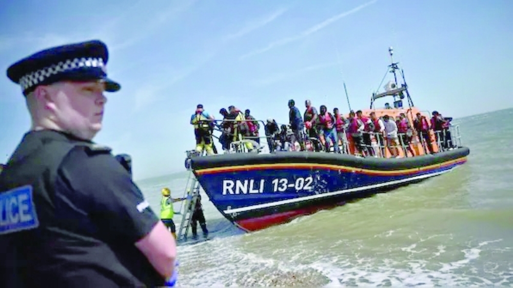 A British police officer stands guard on the beach of Dungeness, on the southeast coast of England, as Royal National Lifeboat Institution's (RNLI) members of staff help migrants to disembark. - AFP File