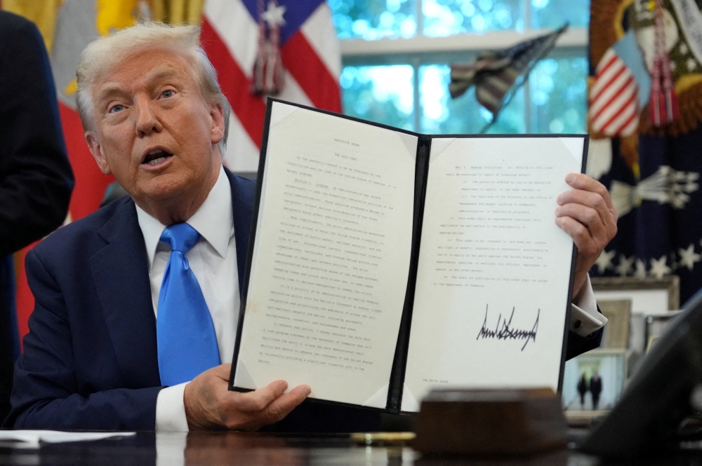 U.S. President Donald Trump displays a signed executive order on a gold card visa in the Oval Office at the White House in Washington