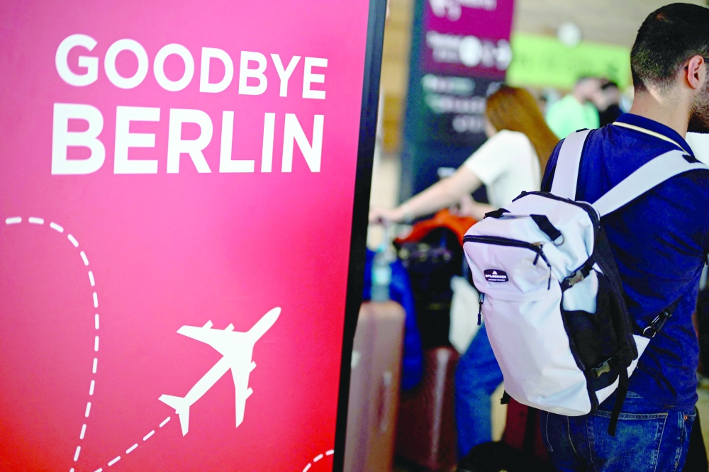 The lettering 'Goodbye Berlin' is seen on a board as a passenger carrying a backpack walks at Terminal 1 of Berlin on Saturday. — AFP