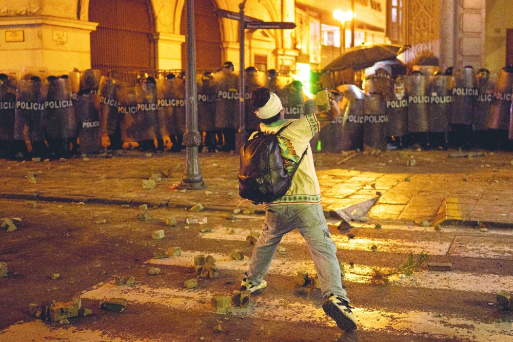 A protester throws a stone as he clashes with riot police during an anti-government demonstration in Lima on September 20, 2025. (Photo by Ernesto BENAVIDES / AFP)