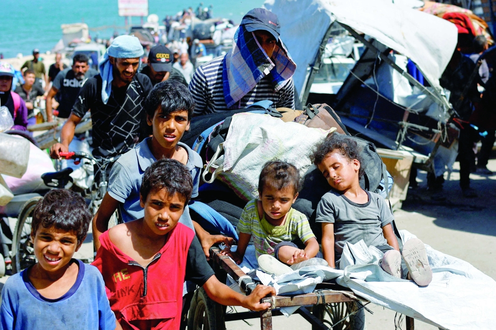 Displaced Palestinian children flee southward with belongings, in Gaza. — Reuters
