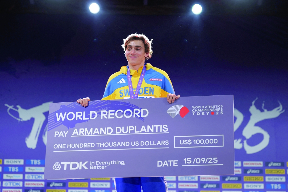 Sweden's Armand Duplantis celebrates on the podium with the prize money cheque for breaking the world record. — Reuters