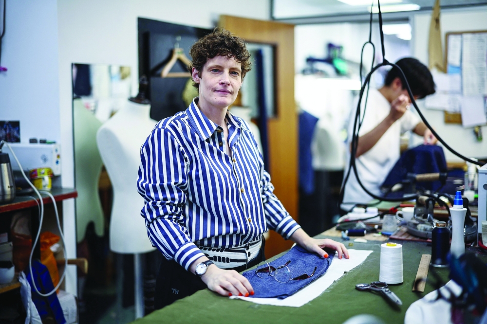 Coat maker Jinny Seals poses at a workstation inside Henry Poole & Co on Savile Row in London on August 12, 2025. Beneath the old-world exterior of a tailors on London's famed Savile Row, the workshop where the magic happens is more youthful than ever as aspiring coatmakers vie for competitive apprenticeships.
 (Photo by HENRY NICHOLLS / AFP)
