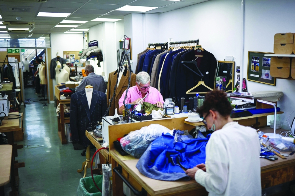 Tailors Roy and Buffy make adjustments to jackets at Henry Poole & Co on Savile Row in London on August 12, 2025. Beneath the old-world exterior of a tailors on London's famed Savile Row, the workshop where the magic happens is more youthful than ever as aspiring coatmakers vie for competitive apprenticeships.
 (Photo by HENRY NICHOLLS / AFP)
