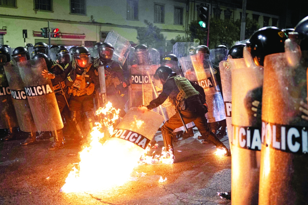 A riot police officer is hit by a Molotov cocktail during an anti-government demonstration in Lima. — AFP