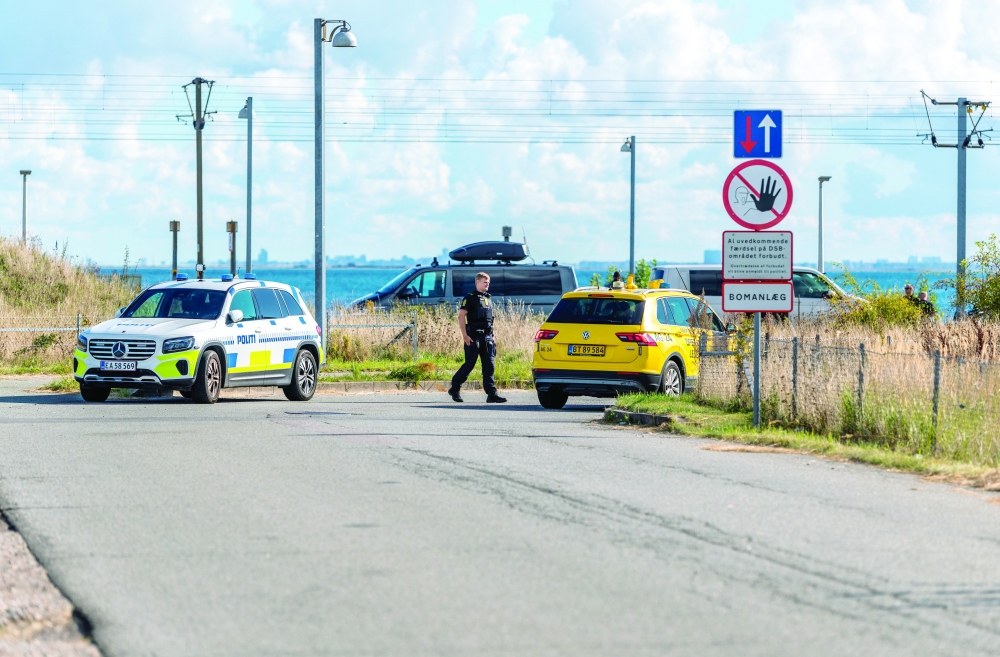 An officer walks next to vehicles after drones were observed in Danish airspace, in Copenhagen. — AFP