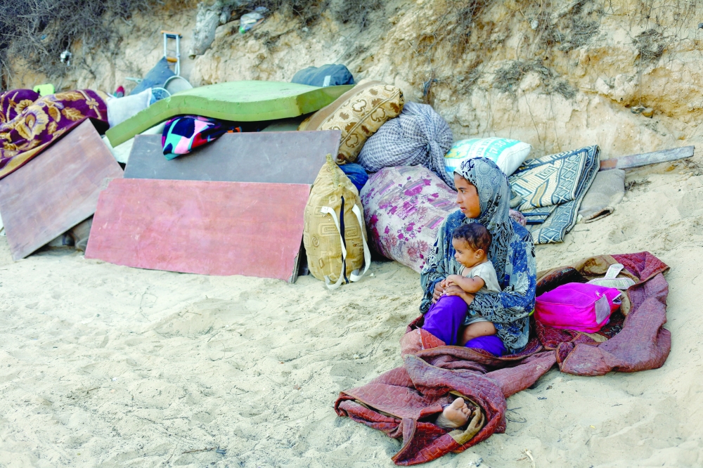 A displaced woman with a child rests after fleeing strikes in Gaza, Palestine. — Reuters
