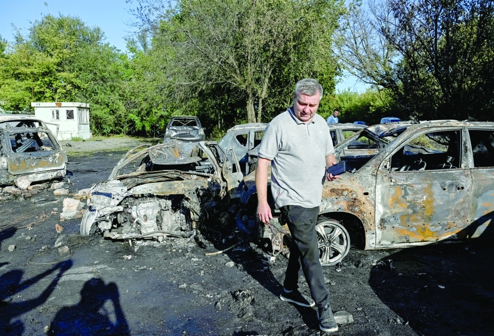A resident walks near burned cars hit by a Russian drone strike, in Zaporizhzhia. — Reuters