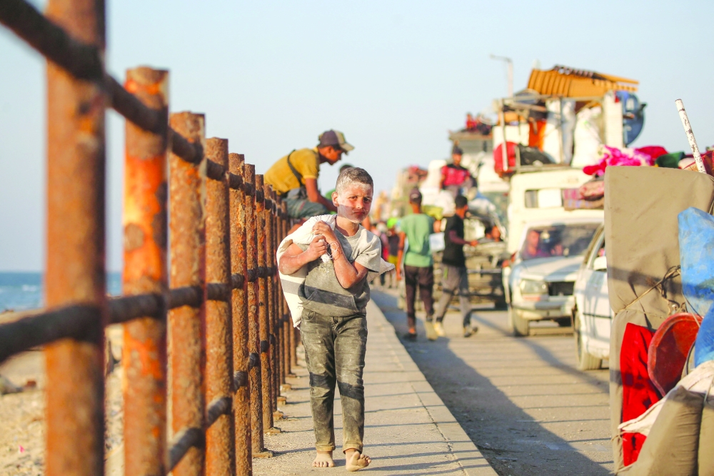 Displaced Palestinians move with their belongings southwards on a road in the Nuseirat refugee camp. — AFP