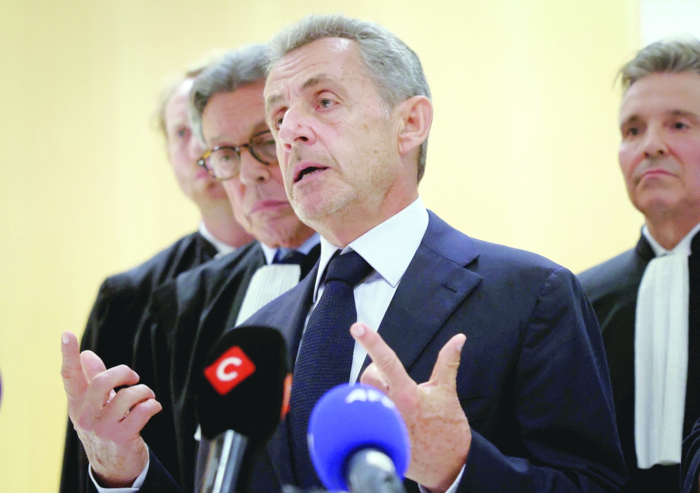 Former French president Nicolas Sarkozy speaks to the press next to his lawyer French Jean-Michel Darrois (2L) after the verdict in his trial for illegal campaign financing from Libya for his successful 2007 presidential bid at the Tribunal de Paris courthouse in Paris. - AFP
