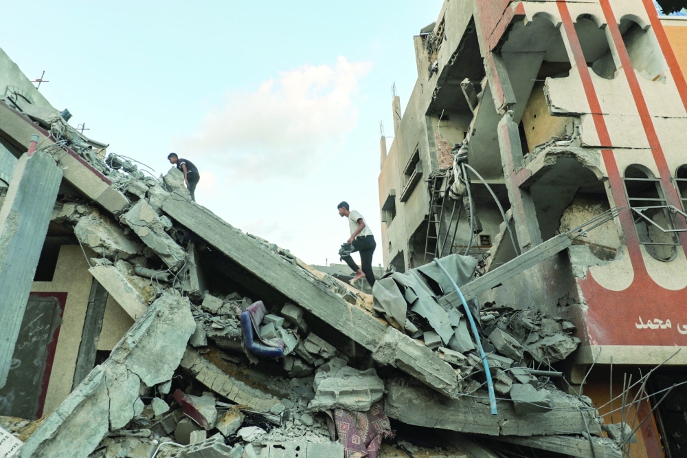 Palestinians check the rubble of a building hit by an Israeli strike in the Nuseirat refugee camp in the central Gaza Strip on Thursday. — AFP