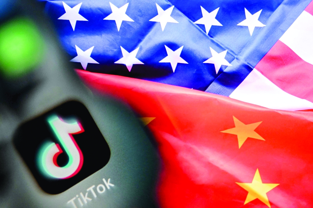 A photo taken on April 10, 2025 shows the Chinese social networking service TikTok's logo on a smartphone screen (L) and US' and China flags combo illustration on a laptop screen in Frankfurt am Main, western Germany. China said on September 26, 2025 it hoped the United States would provide "open and fair" treatment for TikTok and other Chinese companies investing in the country, after President Donald Trump signed an executive order on a proposed deal for a US version of the popular app. (Photo by Kirill KUDRYAVTSEV / AFP)
