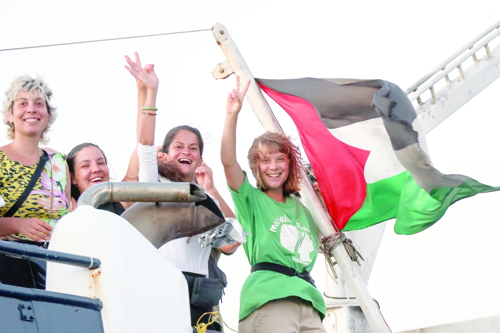 Greta Thunberg and a crew member flash victory signs from their ship, part of the Global Sumud Flotilla aiming to reach Gaza and break Israel's naval blockade, as they sail off Crete island, Greece. — Reuters