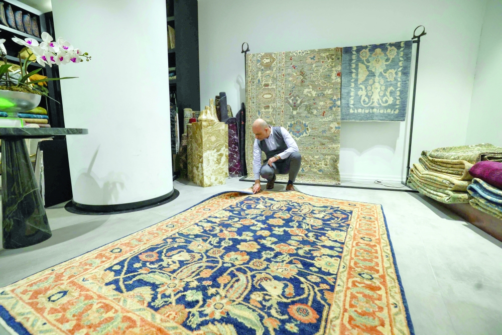 An Iranian man checks a rug at a shop selling antique and expensive carpets in northern Tehran on September 9, 2025. Once a symbol of unmatched artistry and cultural prestige, Iran's handmade rugs are being unwoven from the global tapestry due to international sanctions and domestic pressures. (Photo by ATTA KENARE / AFP)
