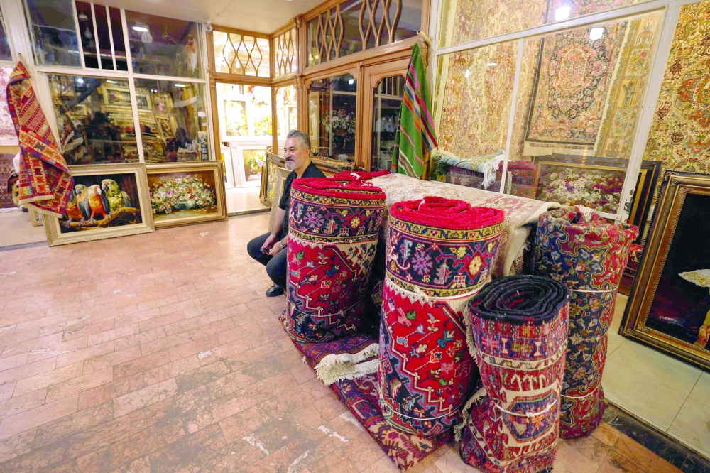 A man sells carpets in Tabriz's historic market, believed to be one of the oldest bazaars in the Middle East, in northwestern Iran, on September 17, 2025. Once a symbol of unmatched artistry and cultural prestige, Iran's handmade rugs are being unwoven from the global tapestry due to international sanctions and domestic pressures. (Photo by ATTA KENARE / AFP)
