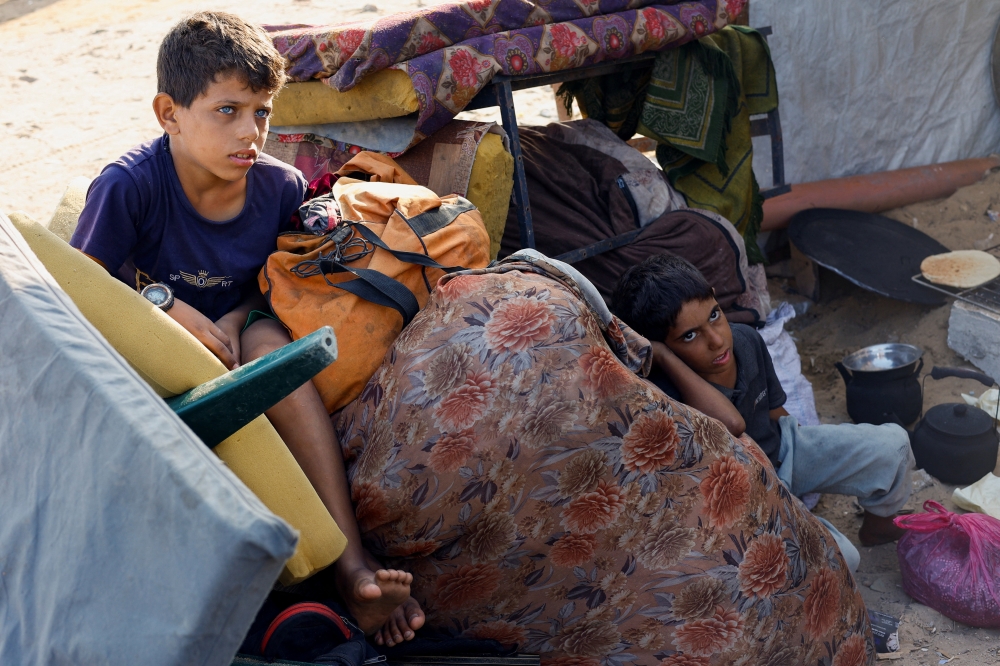Palestinians, who fled northern Gaza after Israeli forces ordered residents of Gaza City to evacuate to the south, rest at their makeshift shelter in the central Gaza Strip, on Saturday. — Reuters