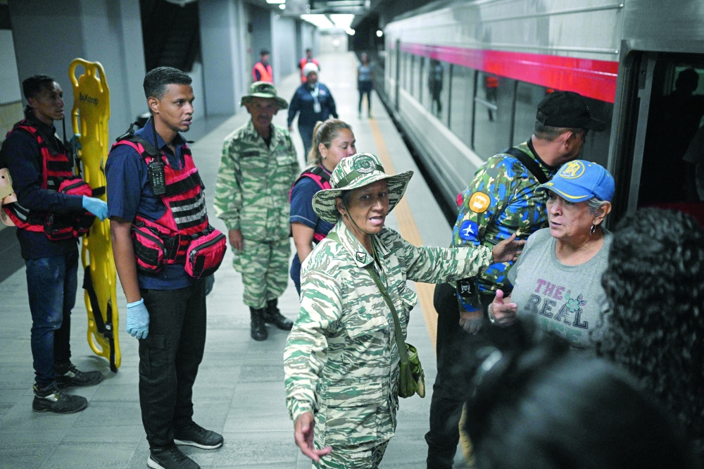 A member of the Bolivarian militia helps people to evacuate a train station behind a Bolivarian militia during a risk reduction drill on natural disasters or armed conflict in Caracas on September 27, 2025. 
