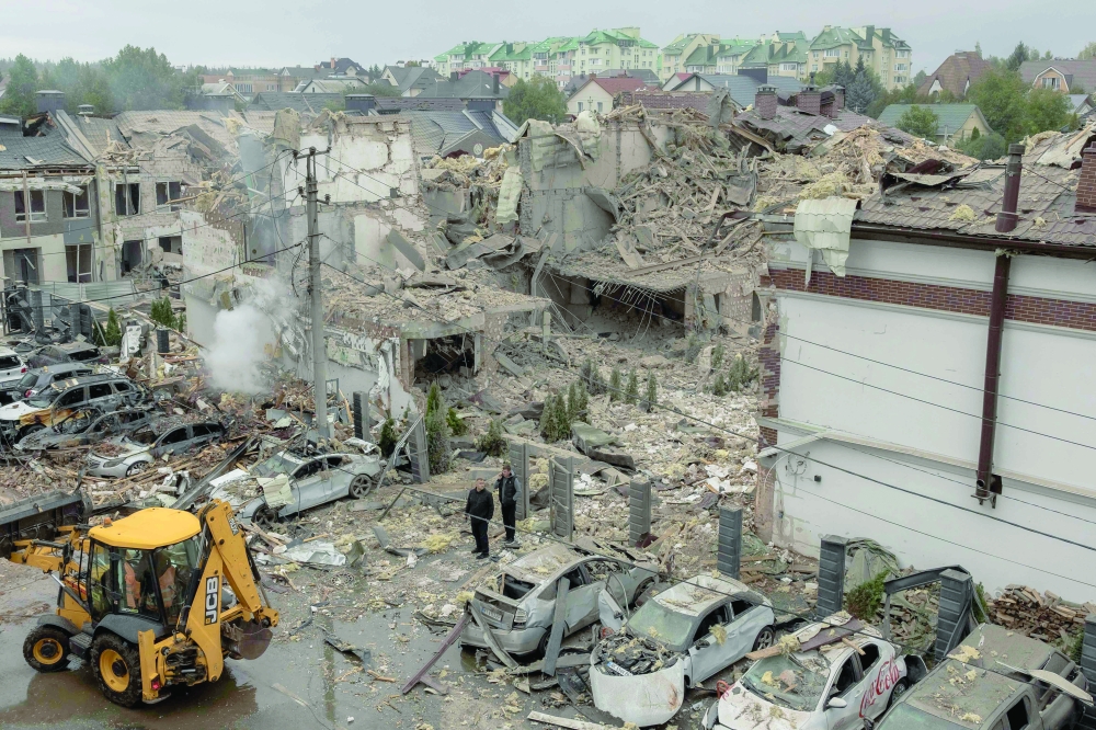 Men stand at the site of heavily damaged buildings following a Russian air attack, in Kyiv. — AFP