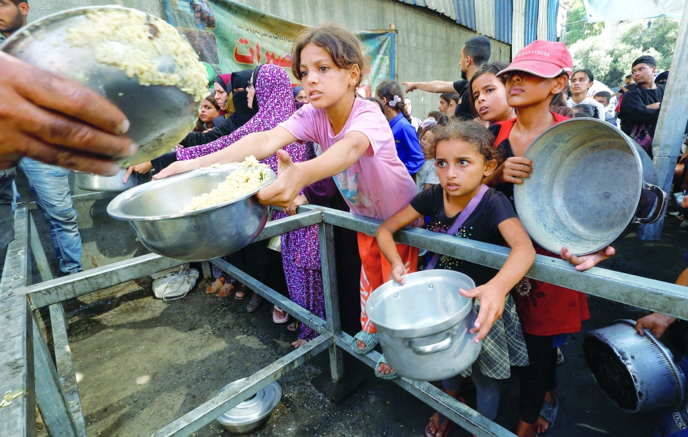 Palestinians gather to receive food from a charity kitchen, in Nuseirat. — Reuters