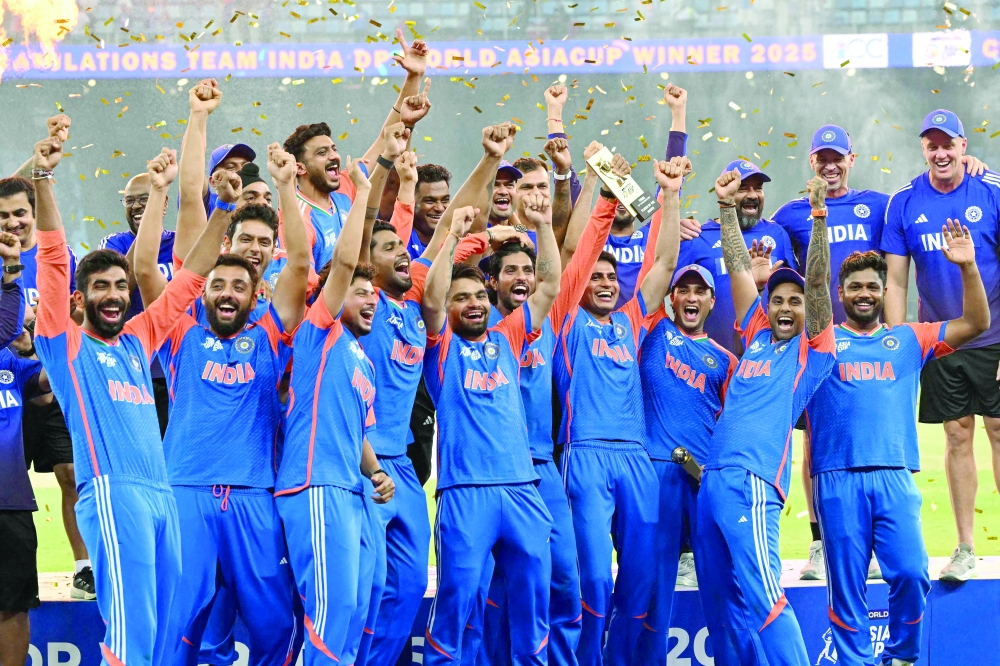 India's captain Suryakumar Yadav (2R) playfully pretends to hold up the trophy as his team celebrates their victory at the end of the Asia Cup 2025 Twenty20 international cricket final match between India and Pakistan at the Dubai International Stadium in Dubai on September 28, 2025.  (Photo by Sajjad HUSSAIN / AFP)
