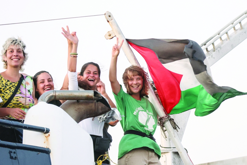 Greta Thunberg and a crew member flash victory signs from their ship as they sail off Crete island, Greece. — Reuters