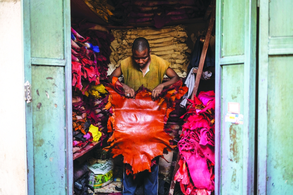 A leather artisan unfolds pieces of dyed skins in his shop at the Kurmi market in Kano, on September 10, 2025. The historic leather hub, Kano, feeds luxury giants like Louis Vuitton, Gucci, and Ralph Lauren, with Nigeria exporting nearly 90% of its hides abroad. But because the finishing work is done in Europe, the “Made in Nigeria” label vanishes, replaced by “Made in Italy” or “Made in Spain.” Now, some Nigerian designers are trying to reclaim the country’s leather identity by building homegrown brands. 
