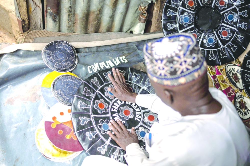 Yahaya Tijjani, a leather artisan, sticks pieces of leather on a pouffe in his workshop at the Kurmi market in Kano, on September 10, 2025. The historic leather hub, Kano, feeds luxury giants like Louis Vuitton, Gucci, and Ralph Lauren, with Nigeria exporting nearly 90% of its hides abroad. But because the finishing work is done in Europe, the “Made in Nigeria” label vanishes, replaced by “Made in Italy” or “Made in Spain.” Now, some Nigerian designers are trying to reclaim the country’s leather identity by building homegrown brands.
